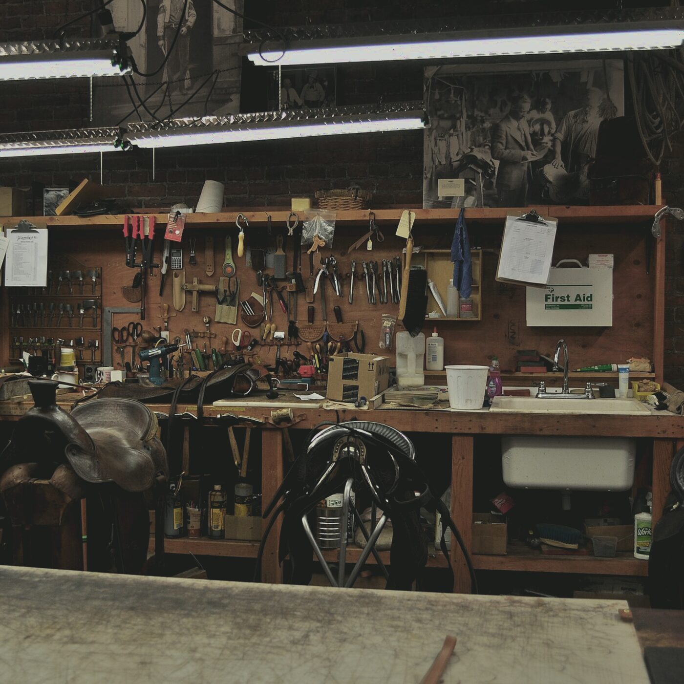 Brass setting tools, awls and hammers hanging above a leather worker's bench